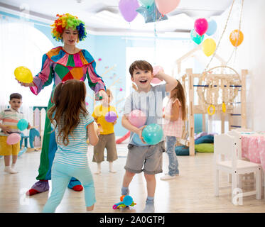 Clown unterhält Kinder Geburtstag. Kinder spielen mit Farben der Ballons Stockfoto