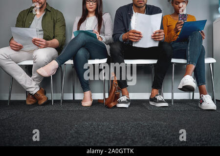 Diverse Kandidaten sitzen in der Warteschlange mit ihren Lebenslauf im Büro ihre Umdrehung für Interview - Jung und multiethnische Gruppe erwartet Stockfoto