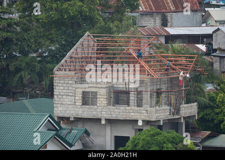 Ein Mann Schweißkolben Dachstühle auf einem privaten Haus in Cebu City, Philippinen Stockfoto