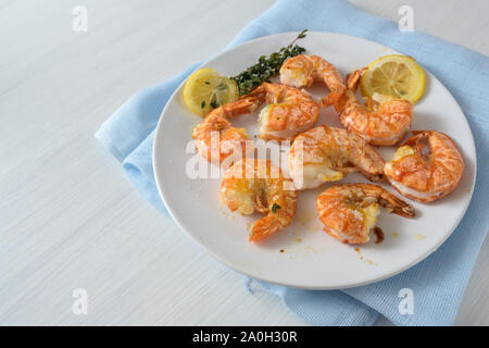 Gebratene Tiger Garnelen Garnelen mit Knoblauch, Zitrone und Kräutern auf einem weissen Teller, Kopieren, ausgewählte konzentrieren, enge Tiefenschärfe Stockfoto