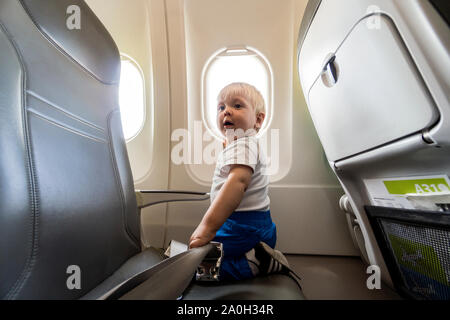Glücklich und aufgeregt, ein Jahr alten baby boy von der Flugzeug Fenster Stockfoto