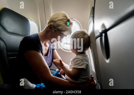 Mutter mit kleinen Baby Sohn spielen im Flugzeug während des Fluges Stockfoto