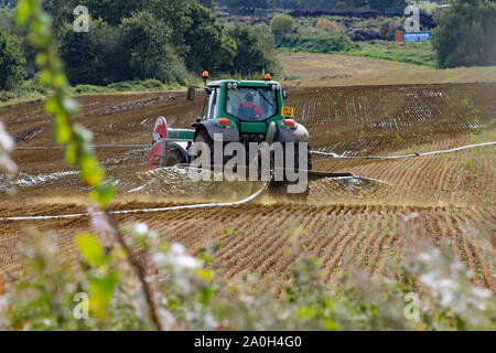 Gülle verbreiten sich in Fortschritt durch ein langes Rohr aus der Farm ein John Deere Traktor in einem Feld in der Nähe von Felder Farm in der Nähe von Sandbach in Cheshire. Stockfoto