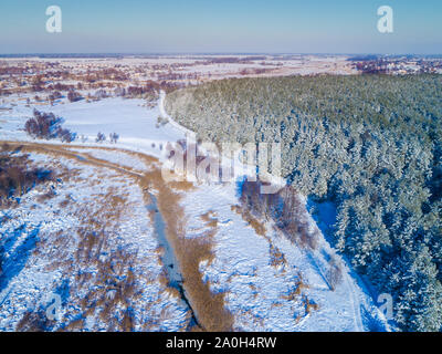 Blick von oben auf den Winter Landschaft am Abend. Felder mit Schnee bedeckt, Wald und gefrorene Creek Stockfoto