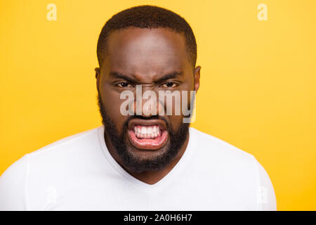 Close-up Portrait von wütenden Wilden manly Böse verrückte mulato Kerl im weißen T-Shirt, die Zähne, die über helle leuchtend gelben Hintergrund isoliert Stockfoto