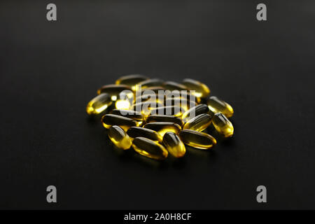 Omega 3 Kapseln auf schwarzen dunklen Hintergrund. Nahrungsergänzungsmittel. Fisch Öl in den Pillen. Gesundheit Unterstützung und Behandlung. Biologisch aktive Zusätze. Vitami Stockfoto