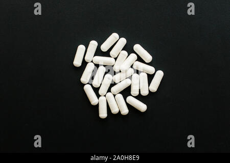 Magnesium Kapseln auf schwarzen dunklen Hintergrund. Flach. Nahrungsergänzungsmittel. Weiße Pille. Gesundheit Unterstützung und Behandlung. Biologisch aktive Zusätze. Stockfoto