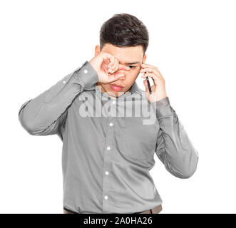 Thai Mann in einem grauen T-Shirt ist, am Telefon zu sprechen und ist traurig. Stockfoto