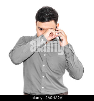 Thai Mann in einem grauen T-Shirt ist, am Telefon zu sprechen und ist traurig. Stockfoto