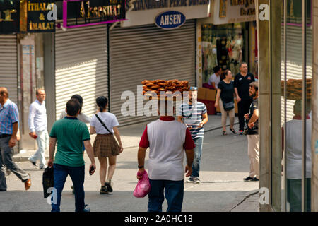 Bagel Verkäufer (wie simit oder Türkischen Bagel bekannt) trägt ein Fach von Bagels auf seinem Kopf, während Menschen zu Fuß durch die Straßen von Eminönü, Istanbul. Stockfoto