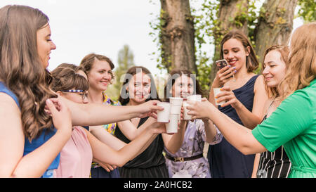 Gruppe Freundinnen Toasten mit Champagner in Papier Glas. Junge Menschen feiern mit Champagner bei der Party im Freien. Konzept der hen-Partei oder corpor Stockfoto