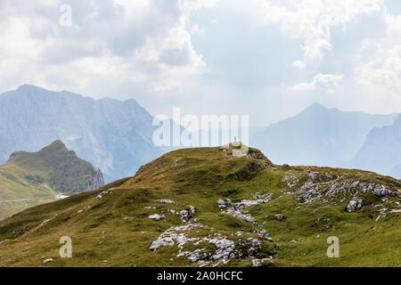 Mann, der allein auf dem Gipfel zwischen riesigen Bergketten in der wunderschönen Natur. Sommer Tag Panorama. Julische Alpen, Nationalpark Triglav, Slowenien. Stockfoto
