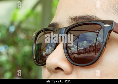 Gesicht Frau tragen braune Sonnenbrille sind auf der Suche nach der Stadt und der Himmel tagsüber. Stockfoto