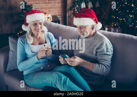 Smart Freund gerät. Zwei nette Leute fröhlich bezaubernd schöne nette Grauhaarige verheiratet Ehegatten Opa Oma sitzend auf der Couch Schlafcouch Sofa im Hou Stockfoto