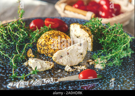 Käse belper Knolle, die in den Gewürzen roten und schwarzen Pfeffer und Kräutern der Provence. Kleine hausgemachte Kugeln von Käse Belper. Delikatesse runde kleine Käse mit Schwarz Stockfoto