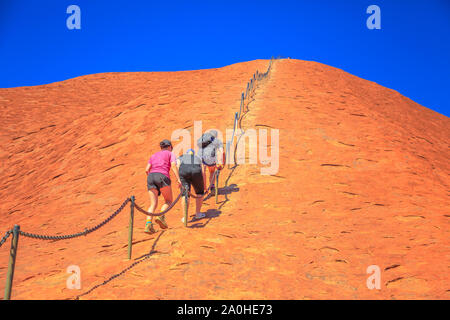 Uluru, Northern Territory, Australien - 23.August 2019: Bergsteiger aufsteigen, Uluru, Kata Tjuta National Park gegen die Wünsche der Aborigines Ana Stockfoto