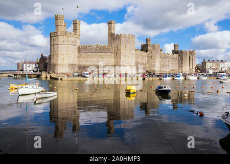 Anzeigen von Edward 1. aus dem 13. Jahrhundert stammenden Schloss in Afon Seiont River bei Flut mit angelegten Boote wider. Caernarfon, Gwynedd, Wales, Großbritannien, Großbritannien Stockfoto