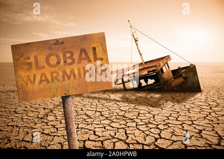 Rostige Schild mit Text "globale Erwärmung" auf dem Hintergrund der alten Schiff in einer getrockneten Ozean. Klimawandel Konzept. Stockfoto