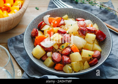 Gebratene Würstchen mit Gemüse wie Kartoffeln, Zwiebeln und Karotten. Einfaches schnelles Rezept für Mittag- oder Abendessen. Stockfoto