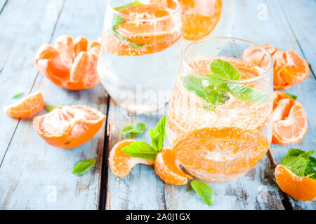 Sommer Mandarine Citrus trinken, Limonade oder Mojito, mit frischen Mandarinen, Zitronen und Minze auf einem blauen Holztisch, Stockfoto