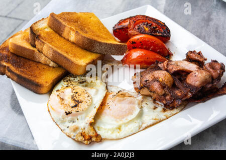 Australischen Frühstück mit Spiegelei, Speck, Tomaten und Toast. Stockfoto