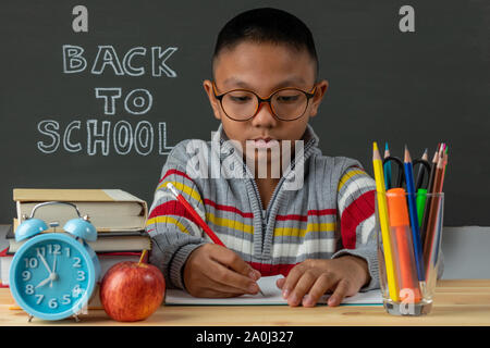 Nachdenklich ein Junge mit Buch im Unterricht. Stockfoto