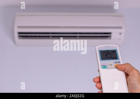 Frau hand Einschalten Klimaanlage 25 Celsius. Energiesparkonzept. Stockfoto