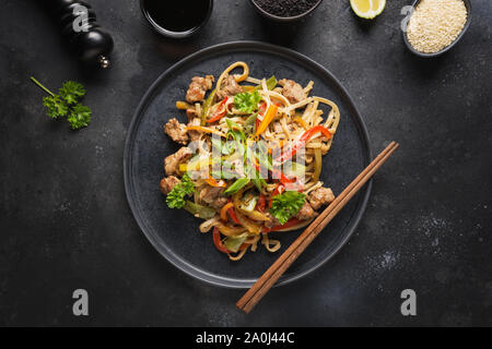 Udon unter Rühren braten Schüssel Nudeln mit Schweinefleisch und Gemüse auf schwarzen Stein Hintergrund. Asiatische Küche. Stockfoto