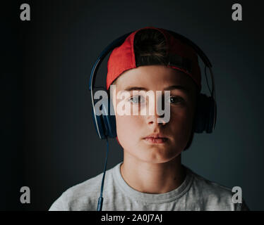 Portrait von tween Junge mit Kopfhörern und rückwärts Ball Cap. Stockfoto