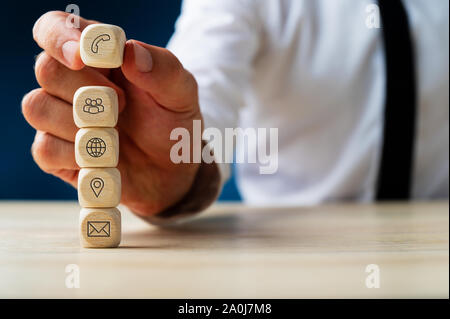 Kundendienstmitarbeiter stapeln Holz- Würfel mit globalen Kontakt- und Standortinformationen Symbole auf Sie. Stockfoto