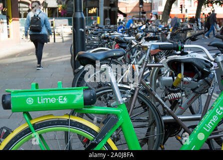 Ein Kalk dockless Elektrofahrrad unter Standard Fahrräder in Hammersmith, London, England Stockfoto