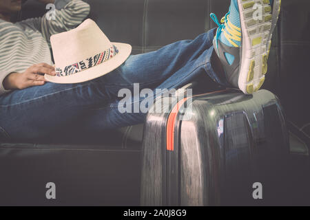 Weibliche Reisende setzt Ihre Beine auf Reisen Tasche während am Flughafen warten. Travel Concept. Stockfoto