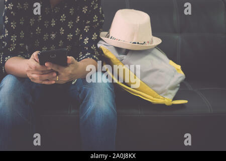 Weibliche Reisende ist entspannend auf leder Sofa holding Handy am Flughafen. Travel Concept. Stockfoto