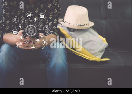 Weibliche Reisende ist entspannend auf leder Sofa holding Handy mit virtuellen Symbol Diagramm am Flughafen. Travel Concept. Stockfoto