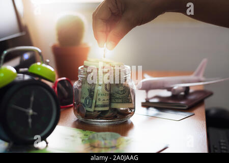 Hand der Leute, die eine Münze in ein Glas. Speichern für Travel Concept. Stockfoto