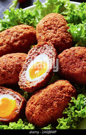 Close-up von Scotch Eier, gekochte Eier in Hackfleisch gewickelt und frittiert, mit salatblätter auf dem Teller serviert, Makro Stockfoto