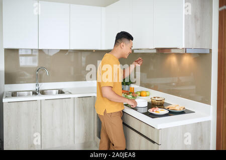 Happy asiatischer Mann Zubereitung von Speisen in der Küche zu Hause. Stockfoto