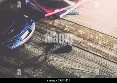 CD-Player mit CD und Kopfhörer auf Holzbrett unter warmen Licht Stockfoto