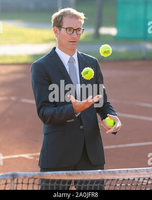 Unternehmer im dunklen Anzug jonglieren mit Tennisbällen auf Tennisplatz Stockfoto