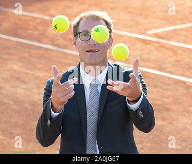 Ansicht von lächelnden Geschäftsmann in dunklen Anzug jonglieren mit Tennisbällen auf Tennisplatz Stockfoto