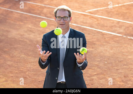 Ansicht von lächelnden Geschäftsmann in dunklen Anzug jonglieren mit Tennisbällen auf Tennisplatz Stockfoto