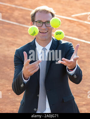 Ansicht von lächelnden Geschäftsmann in dunklen Anzug jonglieren mit Tennisbällen auf Tennisplatz Stockfoto