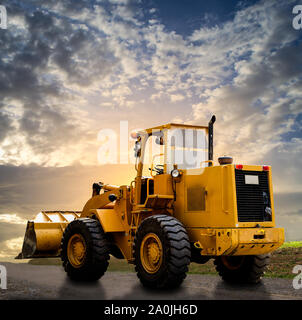 Gelbe Traktor auf der Straße mit bewölkt blauer Himmel Stockfoto