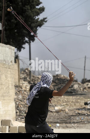 Nablus, Westjordanland, palästinensischen Gebiet. 20 Sep, 2019. Eine palästinensische Demonstranten schleudert einen Stein in Richtung der israelischen Sicherheitskräfte während der Auseinandersetzungen nach einem wöchentlichen Demonstration gegen die Enteignung des palästinensischen Landes durch Israel im Dorf Kfar Qaddum, in der Nähe der Stadt Nablus im Westjordanland am 20. September 2019 Quelle: Shadi Jarar'Ah/APA-Images/ZUMA Draht/Alamy leben Nachrichten Stockfoto