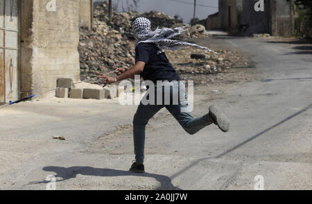 Nablus, Westjordanland, palästinensischen Gebiet. 20 Sep, 2019. Eine palästinensische Demonstranten schleudert einen Stein in Richtung der israelischen Sicherheitskräfte während der Auseinandersetzungen nach einem wöchentlichen Demonstration gegen die Enteignung des palästinensischen Landes durch Israel im Dorf Kfar Qaddum, in der Nähe der Stadt Nablus im Westjordanland am 20. September 2019 Quelle: Shadi Jarar'Ah/APA-Images/ZUMA Draht/Alamy leben Nachrichten Stockfoto