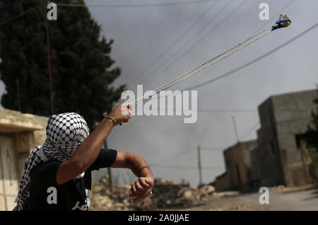 Nablus, Westjordanland, palästinensischen Gebiet. 20 Sep, 2019. Eine palästinensische Demonstranten schleudert einen Stein in Richtung der israelischen Sicherheitskräfte während der Auseinandersetzungen nach einem wöchentlichen Demonstration gegen die Enteignung des palästinensischen Landes durch Israel im Dorf Kfar Qaddum, in der Nähe der Stadt Nablus im Westjordanland am 20. September 2019 Quelle: Shadi Jarar'Ah/APA-Images/ZUMA Draht/Alamy leben Nachrichten Stockfoto