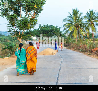 Indische Frauen in Sari zu Fuß die Straße runter, Puttaparthi, Indien. Ansicht von hinten. Stockfoto