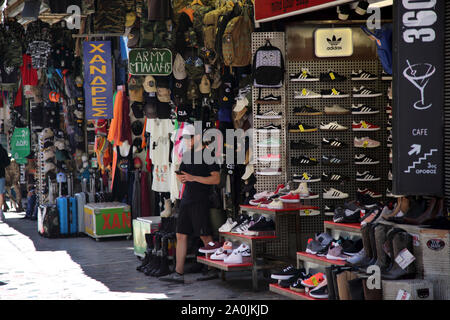 Monasteraki Athen Griechenland Basar Flohmarkt Schuhe zum Verkauf - Mann von SMS-Nachrichten auf dem Smartphone Stockfoto