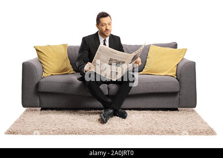 In voller Länge Porträt einer jungen Geschäftsmann sitzt auf einem Sofa und las eine Zeitung auf weißem Hintergrund Stockfoto