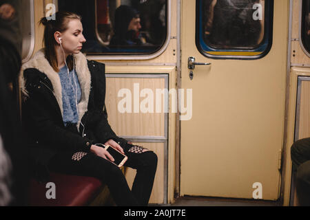 Junge Frau hört Musik auf Smart Phone in der U-Bahn Stockfoto